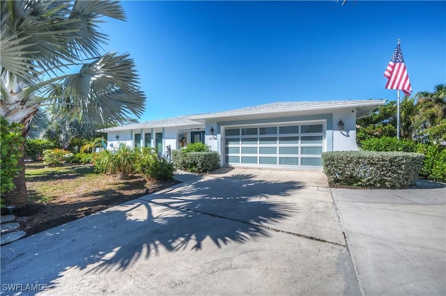 view of front of house with concrete driveway, an attached garage, and stucco siding