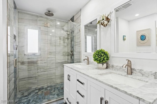 full bathroom featuring double vanity, a stall shower, a sink, and visible vents