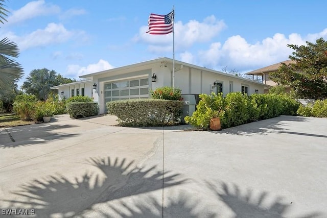 exterior space with concrete driveway, an attached garage, and stucco siding