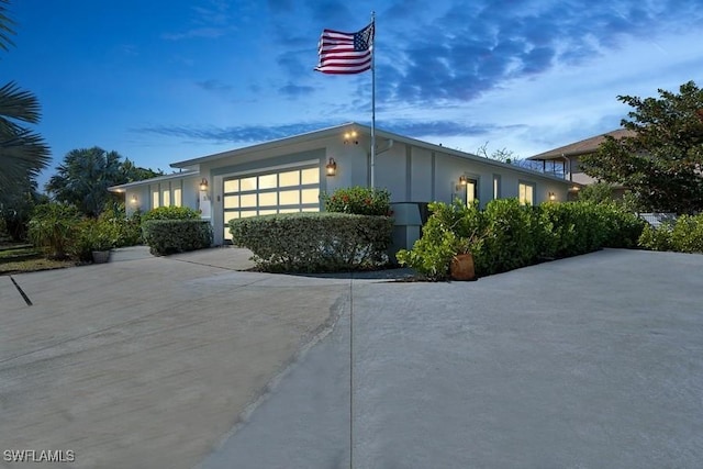 view of front facade with a garage, concrete driveway, and stucco siding