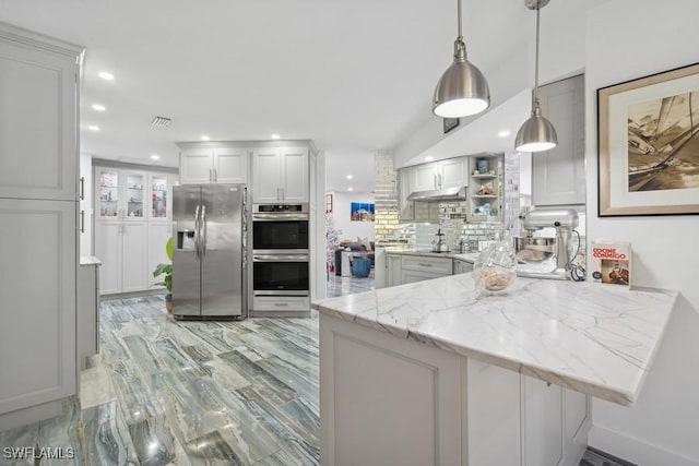 kitchen with stainless steel appliances, visible vents, backsplash, light stone countertops, and a peninsula