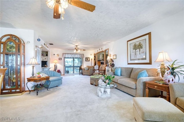 carpeted living room featuring ceiling fan and a textured ceiling