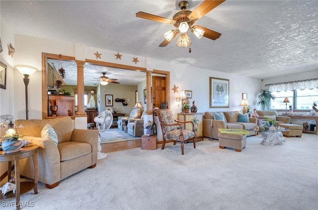 carpeted living room with ornate columns, ceiling fan, and a textured ceiling