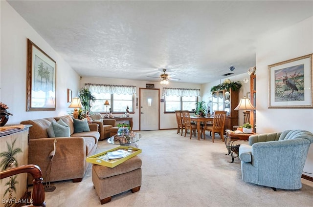 living room with a textured ceiling, ceiling fan, and light carpet