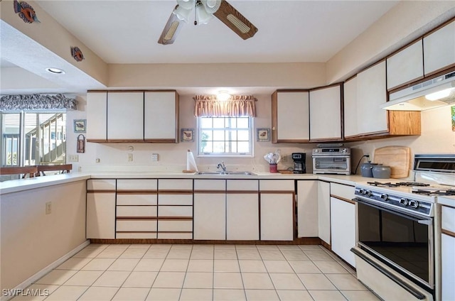 kitchen with white cabinets, a wealth of natural light, white gas range, and sink