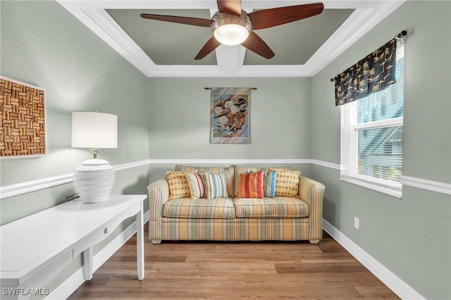 living area with wood-type flooring, a tray ceiling, ceiling fan, and crown molding