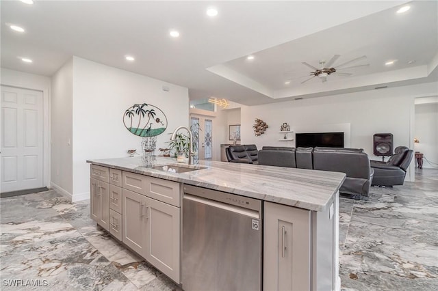 kitchen featuring light stone countertops, ceiling fan, a kitchen island with sink, sink, and dishwasher