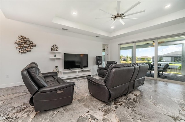 living room with a raised ceiling and ceiling fan