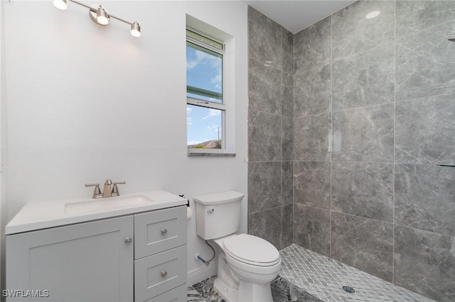 bathroom featuring tiled shower, vanity, and toilet