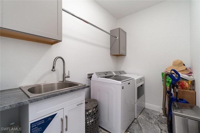 clothes washing area featuring washing machine and clothes dryer, sink, and cabinets