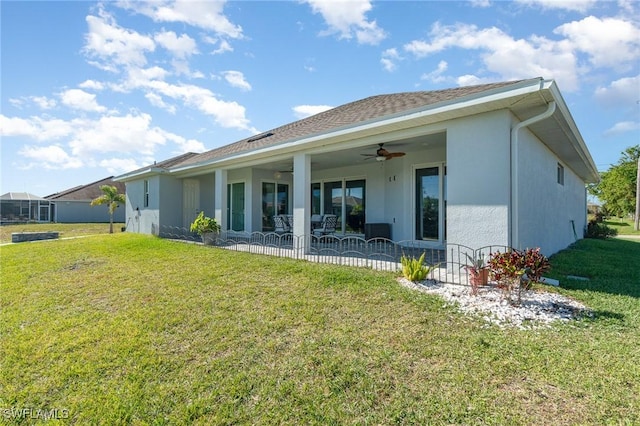 back of house with ceiling fan and a yard