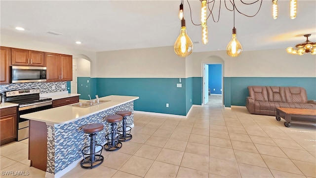 kitchen featuring appliances with stainless steel finishes, a notable chandelier, pendant lighting, and sink