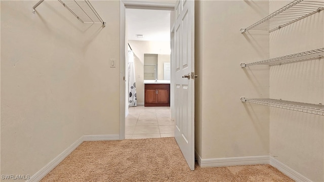 walk in closet with light carpet