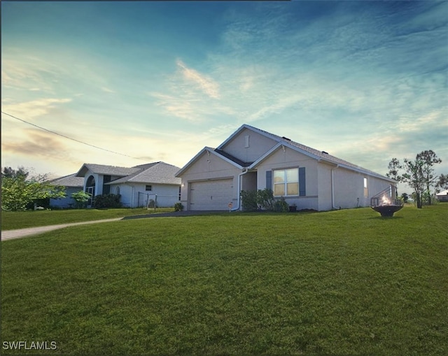 single story home featuring a lawn and a garage