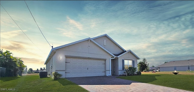 view of front of property with a garage, a yard, and central air condition unit