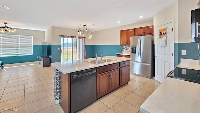 kitchen featuring sink, hanging light fixtures, stainless steel appliances, an island with sink, and light tile patterned flooring