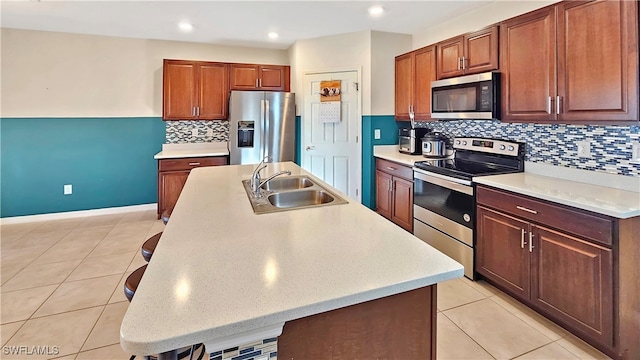 kitchen featuring a kitchen bar, sink, an island with sink, and appliances with stainless steel finishes