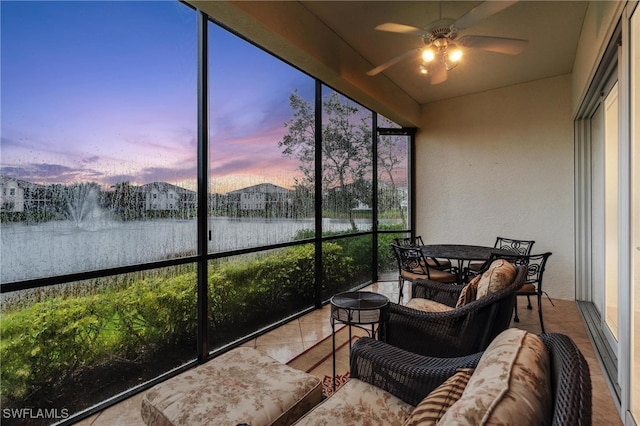 sunroom featuring a water view, ceiling fan, and a healthy amount of sunlight