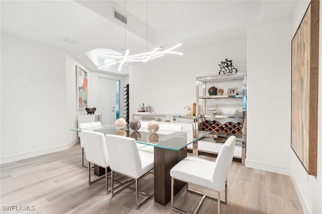 dining room with light hardwood / wood-style flooring and a notable chandelier