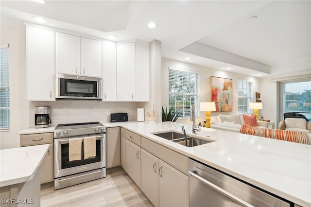 kitchen with white cabinetry, light stone countertops, sink, appliances with stainless steel finishes, and light wood-type flooring