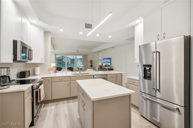 kitchen with sink, kitchen peninsula, light hardwood / wood-style floors, a kitchen island, and appliances with stainless steel finishes