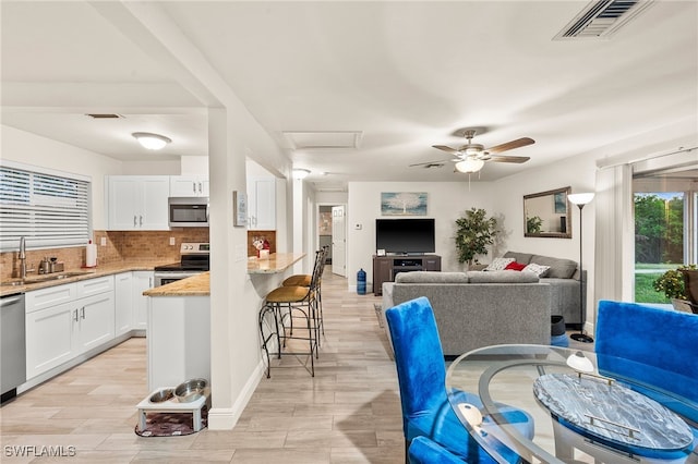 kitchen with white cabinets, sink, a breakfast bar area, light stone counters, and stainless steel appliances