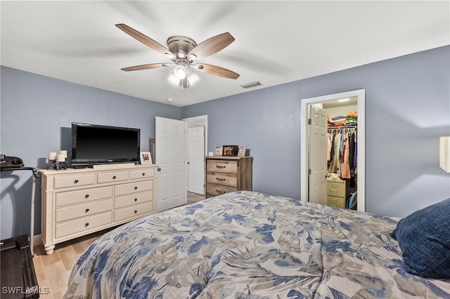 bedroom featuring ceiling fan, a closet, light hardwood / wood-style floors, and a spacious closet