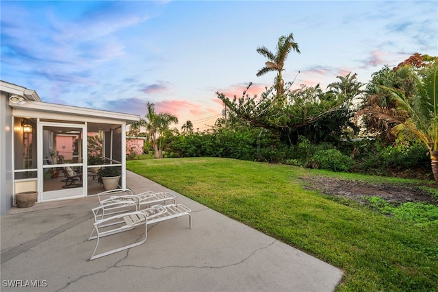 yard at dusk with a sunroom and a patio