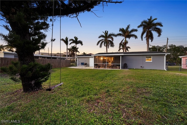 yard at dusk featuring a sunroom