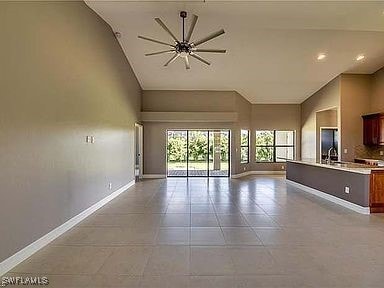 unfurnished living room with light tile patterned floors, vaulted ceiling, ceiling fan, and sink