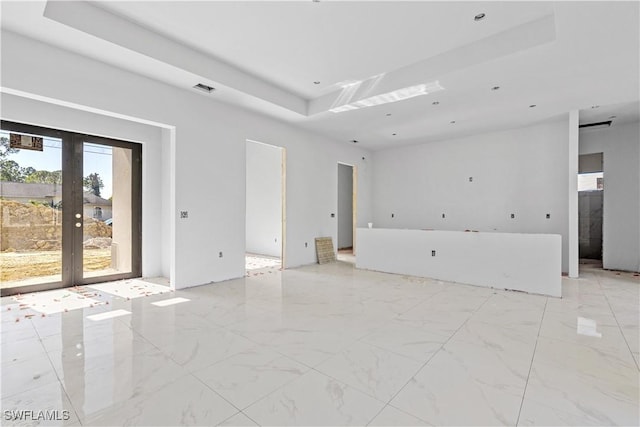 spare room featuring a raised ceiling and french doors