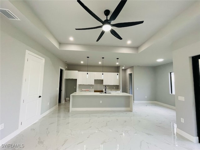 kitchen featuring baseboards, visible vents, white cabinetry, and a raised ceiling