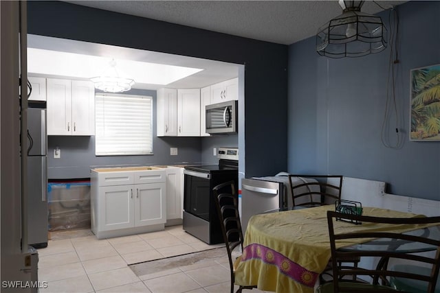 kitchen featuring white cabinetry, pendant lighting, a textured ceiling, light tile patterned flooring, and appliances with stainless steel finishes