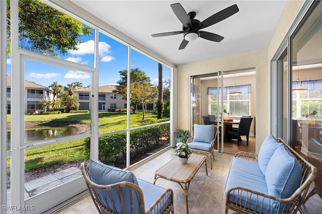 sunroom / solarium with a wealth of natural light, a ceiling fan, and a water view