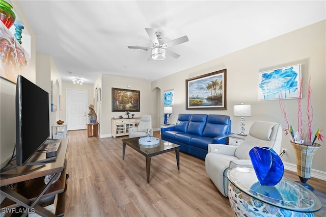 living area with light wood-style flooring, baseboards, and ceiling fan