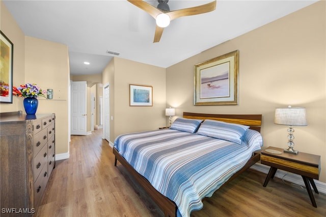 bedroom featuring visible vents, ceiling fan, baseboards, wood finished floors, and a closet