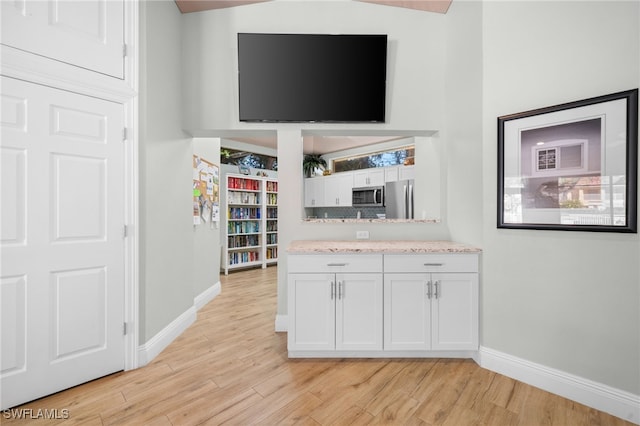 kitchen with baseboards, light wood finished floors, light countertops, white cabinets, and appliances with stainless steel finishes