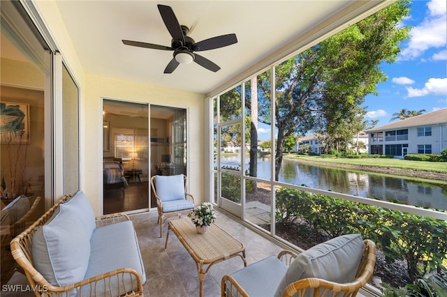 sunroom with ceiling fan and a water view