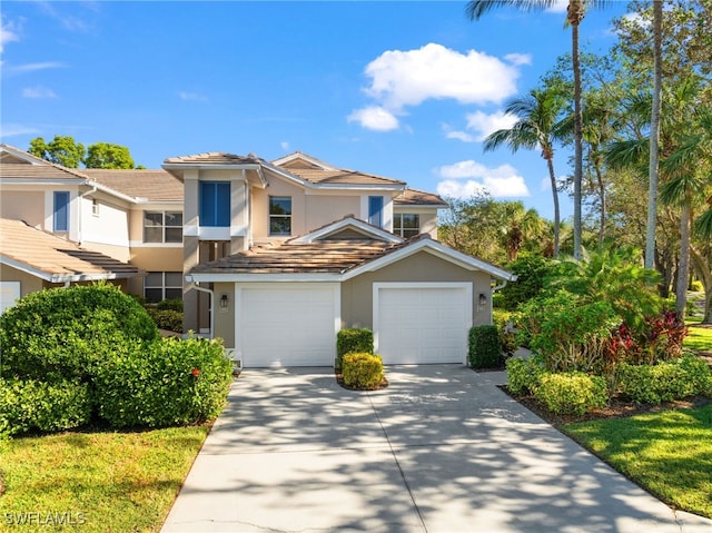 view of front of property featuring a garage, a tile roof, concrete driveway, and stucco siding