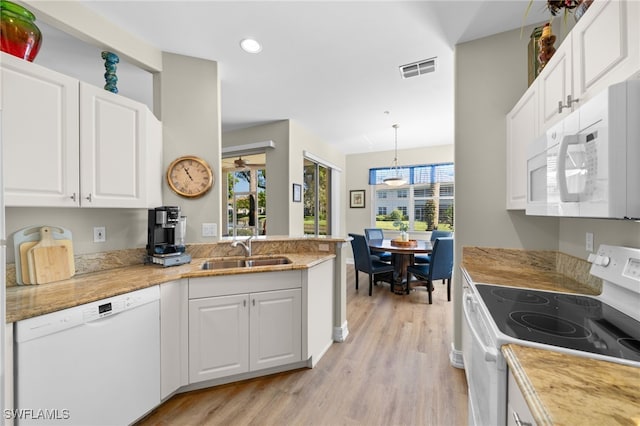 kitchen with white appliances, a sink, white cabinets, light countertops, and pendant lighting