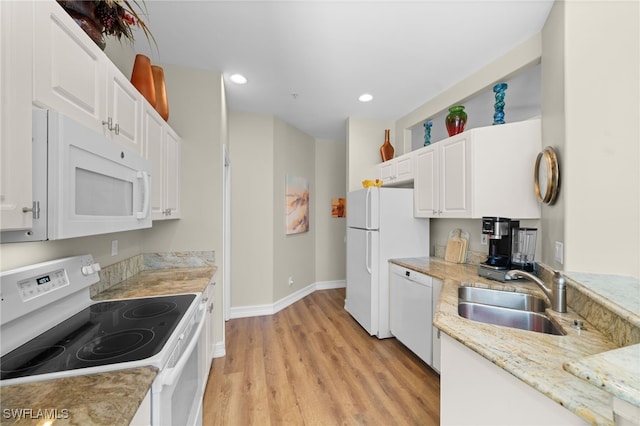 kitchen featuring white appliances, white cabinets, light stone counters, light wood-style floors, and a sink