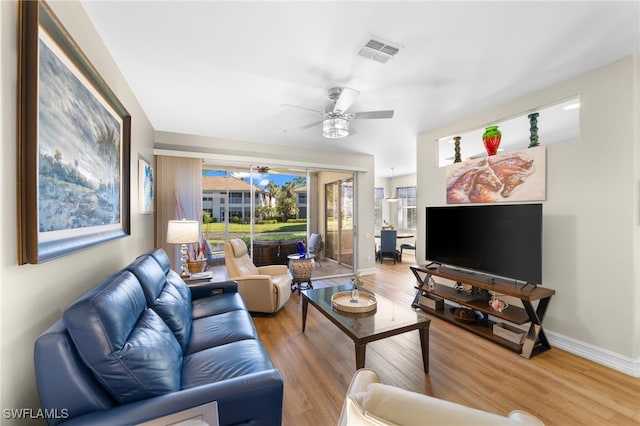 living room featuring a ceiling fan, light wood-style floors, visible vents, and baseboards