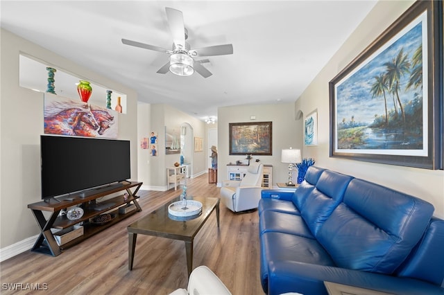 living room with ceiling fan, arched walkways, wood finished floors, and baseboards