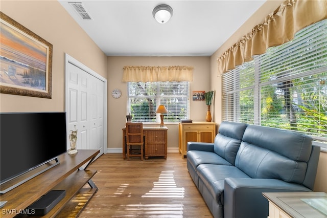 living area with wood finished floors, visible vents, and baseboards