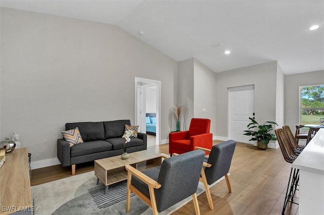 living room with light hardwood / wood-style floors and vaulted ceiling