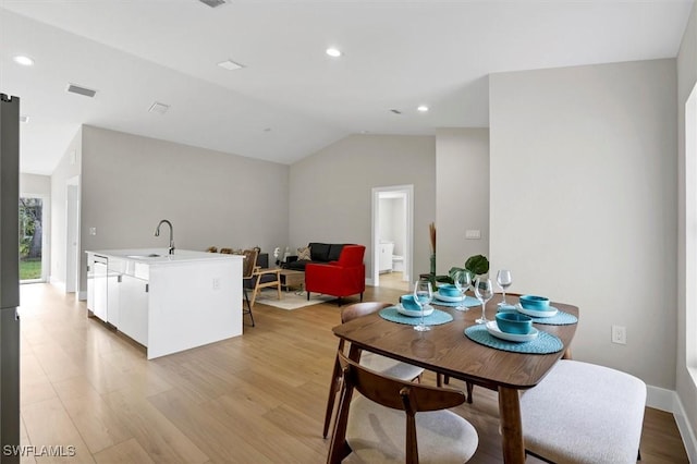 dining room with light wood-type flooring, lofted ceiling, and sink