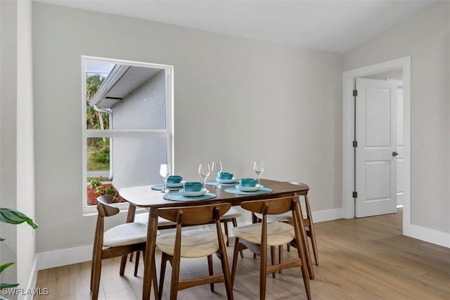 dining area with light wood-type flooring and lofted ceiling