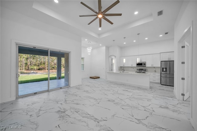 unfurnished living room featuring ceiling fan, a raised ceiling, and sink