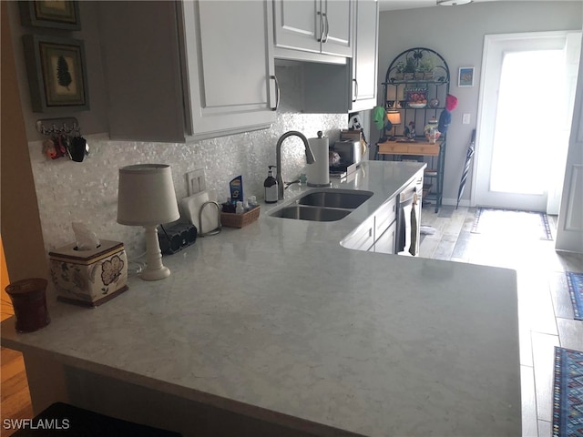 kitchen with tasteful backsplash, stainless steel dishwasher, sink, light hardwood / wood-style flooring, and white cabinetry