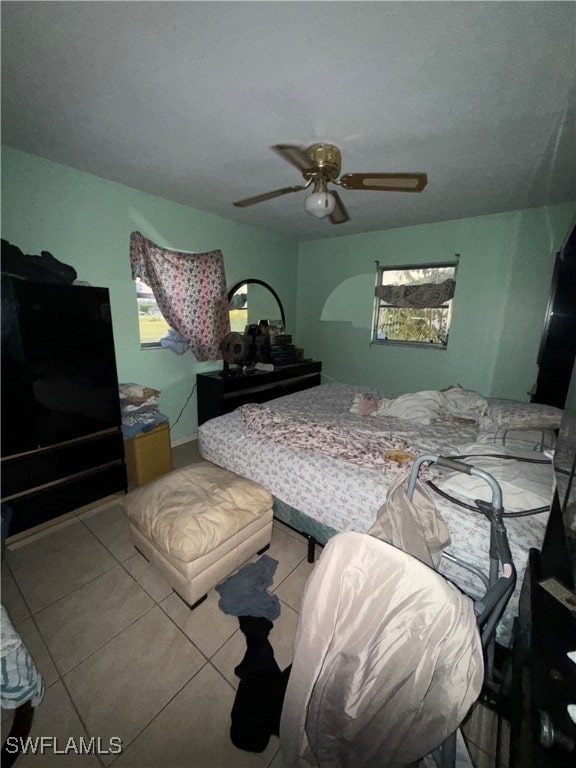 tiled bedroom featuring multiple windows and ceiling fan